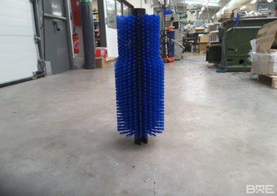Une brosse rotative cylindrique avec un garnissage spécifique, conçue pour le nettoyage et le polissage des bouteilles dans une machine d'embouteillage.