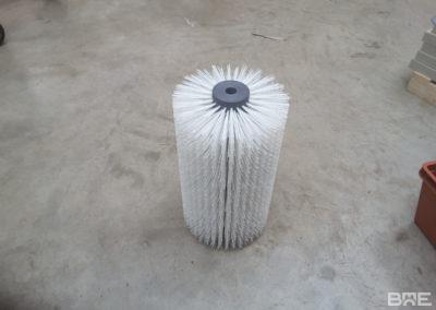 Une brosse rotative à poils longs est présentée, fixée sur un support métallique. Elle est utilisée pour le brossage des carottes dans le secteur agricole.