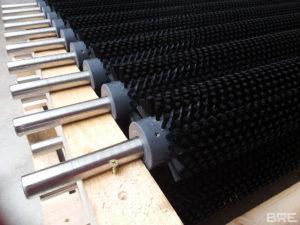 Une série de brosses rotatives fixées sur une machine de nettoyage industriel. Ces brosses servent à éliminer les saletés et les impuretés des fruits et légumes lors du processus de lavage.