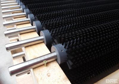 Une série de brosses rotatives fixées sur une machine de nettoyage industriel. Ces brosses servent à éliminer les saletés et les impuretés des fruits et légumes lors du processus de lavage.