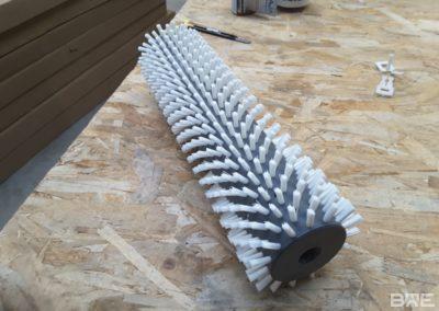 Une brosse rotative avec des soies rigides fixées sur un support cylindrique, conçue pour le nettoyage efficace des oignons en milieu industriel.