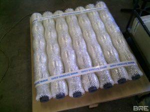 Une série de brosses cylindriques à garnissage dense pour le nettoyage des pommes de terre dans une ligne de conditionnement agroalimentaire.