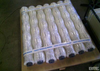 Une série de brosses cylindriques à garnissage dense pour le nettoyage des pommes de terre dans une ligne de conditionnement agroalimentaire.