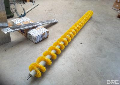 Brosse hélicoïdale conçue pour le mélange et le transport de grains en milieu agricole. La brosse présente une structure en spirale avec des poils rigides, fixés sur un support central.