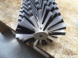 Une brosse rotative avec un garnissage composé de deux matières distinctes est présentée. Cette brosse est conçue pour être utilisée sur une machine de nettoyage de panneaux solaires.