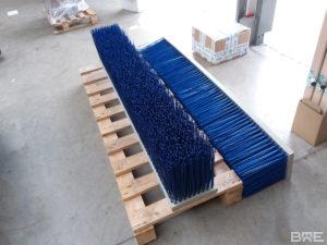 Un balai pousseur robuste fixé aux fourches d'un engin de manutention pour le nettoyage efficace des sols dans les environnements agricoles et industriels.