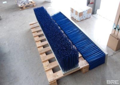Un balai pousseur robuste fixé aux fourches d'un engin de manutention pour le nettoyage efficace des sols dans les environnements agricoles et industriels.