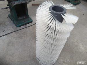 Une brosse cylindrique hélicoïdale conçue pour le nettoyage efficace des bandes transporteuses dans les environnements industriels.