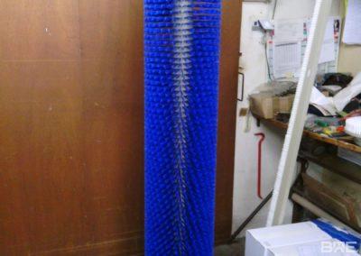 Une brosse rotative de grande longueur pour le nettoyage des haricots. La brosse est montée sur un cadre métallique robuste et est entraînée par un moteur électrique. Les poils de la brosse sont en nylon et sont suffisamment rigides pour enlever la saleté et les débris des haricots sans les endommager.